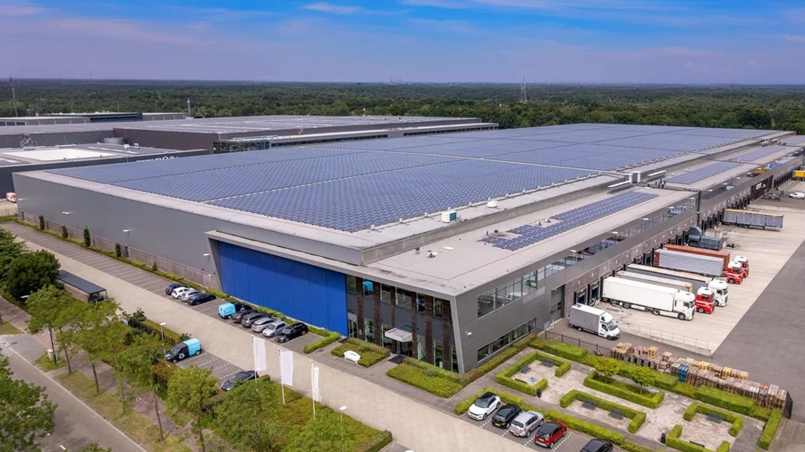 Aerial view of large industrial warehouse with solar panels on the roof