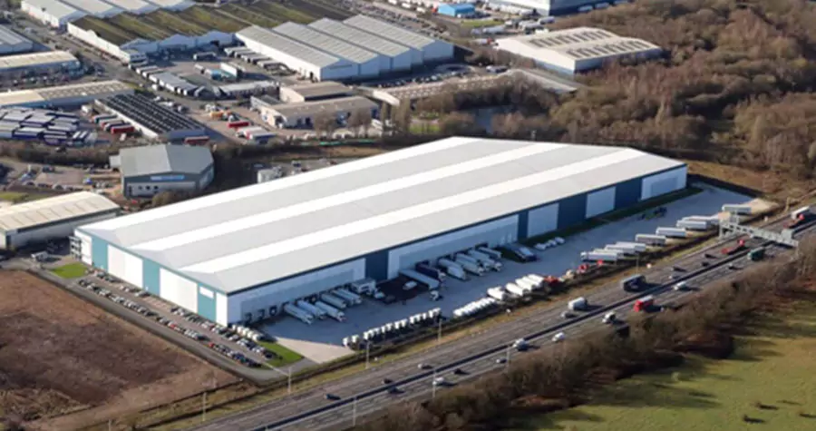 Aerial of large industrial warehouse next to highway