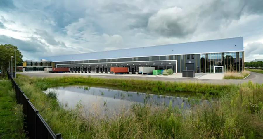 Exterior of an industrial warehouse with a grassy pond in the foreground