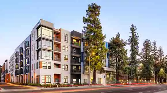 5-story apartment building on street corner with palm trees